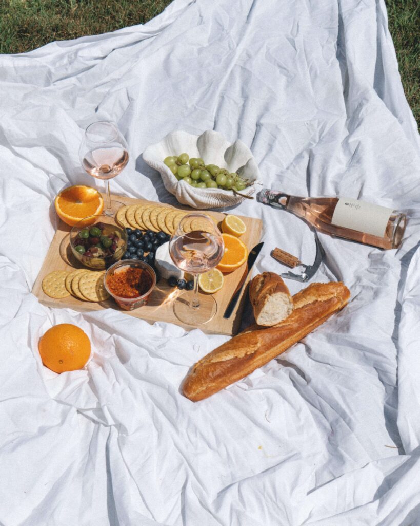 Foto van een gezellige picknick op een wit laken met een stokbrood en een fles witte wijn